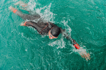 A triathlete in a professional swimming suit trains on the river while preparing for Olympic...