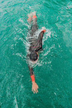 A triathlete in a professional swimming suit trains on the river while preparing for Olympic swimming