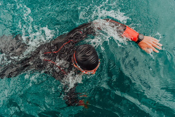 A triathlete in a professional swimming suit trains on the river while preparing for Olympic...