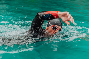 A triathlete in a professional swimming suit trains on the river while preparing for Olympic...