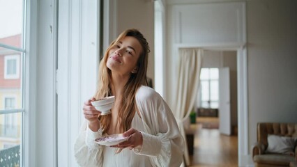 Positive girl drinking tea home portrait. Smiling woman posing camera at house