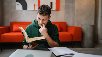 Obraz premium Young man caucasian teenager read book study at home education concept
