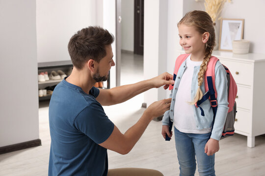 Happy father preparing his smiling daughter to school at home