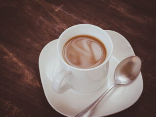 White cup latte coffee on vintage wooden table in morning