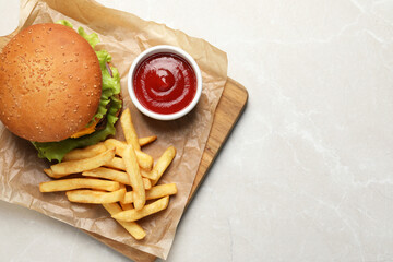 French fries, tasty burger and sauce on white marble table, top view. Space for text