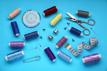 Flat lay composition with thimbles and different sewing tools on light blue background