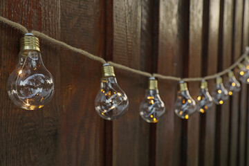 Garland of lamp bulbs hanging on wooden wall. String lights