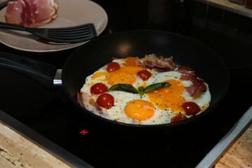 Tasty fried eggs with tomatoes and bacon for breakfast