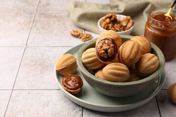 Delicious nut shaped cookies with boiled condensed milk on light textured table, closeup