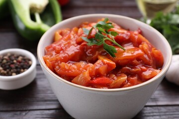 Bowl of delicious lecho with parsley on black wooden table, closeup
