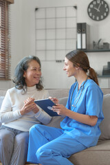 Portrait of attractive young caucasian female nurse elderly caregivers with senior patient home caring for elderly asia female patients on couch, indoors.
