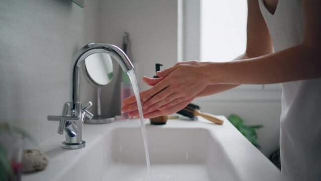 Woman washing hands faucet at home closeup. Unknown lady using bathroom sink