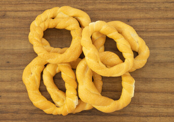 Pieces of traditional Latin American pastry called ROSQUITAS DE SAL or ROSCAS made with wheat flour. Top view of Neapolitan cookies called TARALLI. Stale salt bagels. Wood table. Ecuador