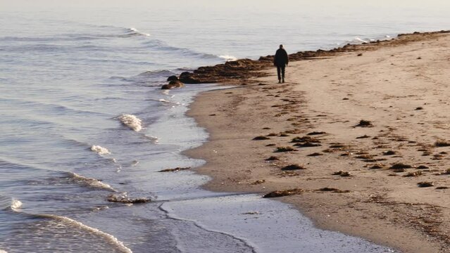 Man Walks Alone on Beach in Semaphore During a Winter Morning