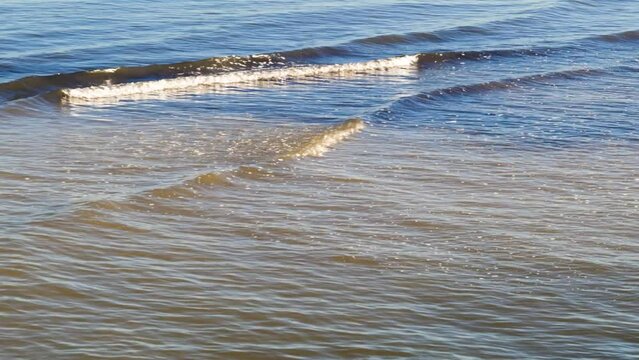 Small Waves Roll into Coast under Ocean Horizon