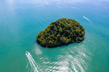 Aerial view of an island and long tail boats passing by on sunny day. Ao Nang Bay, Krabi Province,...