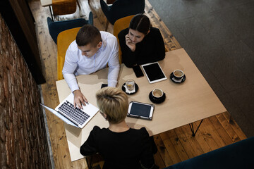 Three young business colleagues having a meeting in a modern cafe in the late evening hours. Successfull startup team analysing data after work hours.