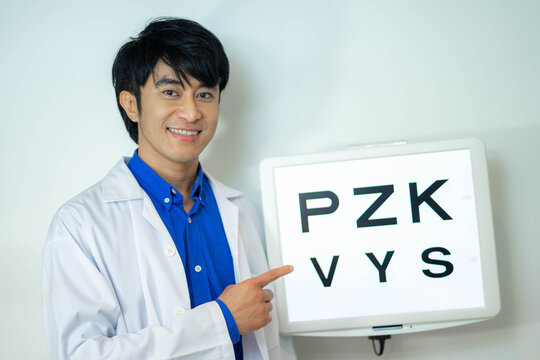 Asian optician man standing by eyesight test with a big smile on face