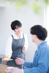 Fototapeta premium 朝食やコーヒーを運んでくる奥さん 見つめ合うカップル