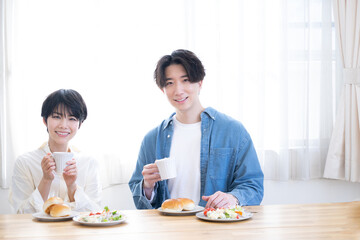 朝食を仲良く食べる新婚さんのイメージ　カメラ目線　右にコピースぺースあり