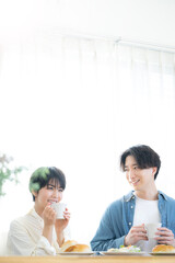 メインビジュアルにも！朝食を仲良く食べる新婚さんのイメージ　見つめ合う　縦