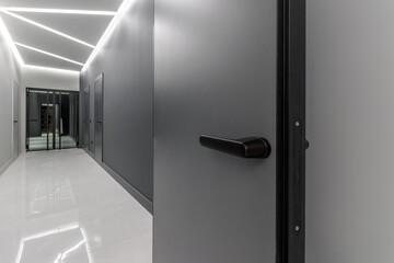 Simple clean newly built generic modern new real estate block of flats interior, long black corridor with black doors, perspective. New bought apartment, new home, hallway abstract concept, copy space