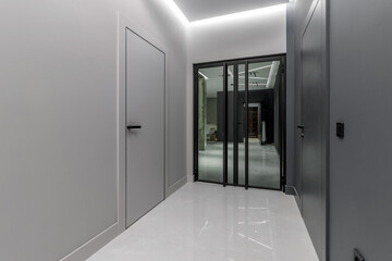 Simple clean newly built generic modern new real estate block of flats interior, long black corridor with black doors, perspective. New bought apartment, new home, hallway abstract concept, copy space