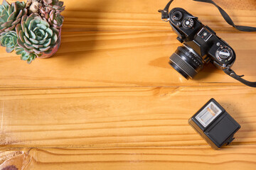 Top view of analog camera and flash on wooden table, professional photography equipment. Photography background with copy space.