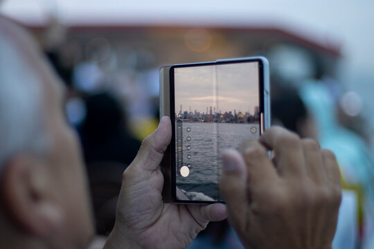 New York, NY, USA - July 8, 2022: Taking a picture with a Samsung Galaxy Fold smartphone during the evening Hudson River cruise tour.