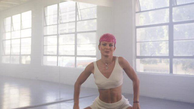 Sexy confident young girl with short pink hair actively dancing in mirror wall studio. Dance class with modern moves shown by beautiful hipster millennial teacher professional dance trainer 4K footage