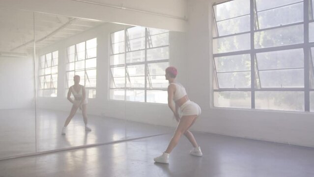 Funky girl with pink hair performing cool dance at mirror glass studio wall. Concept of learning modern hip hop and break dance technique. Youth subculture Contemporary choreography RED camera footage