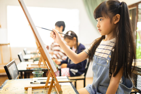 Group of children drawing in classroom, young girl happy funny study and play painting acrylic color on canvas.Young girl happy funny study and play painting on paper at elementary school.