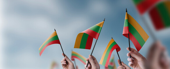 A group of people holding small flags of the Lithuania in their hands - obrazy, fototapety, plakaty