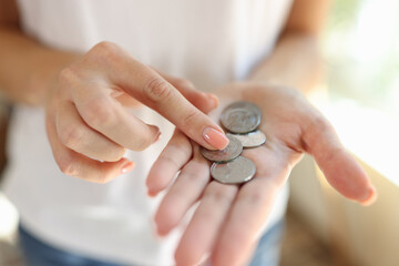 Woman counting small coins in her hands close-up.