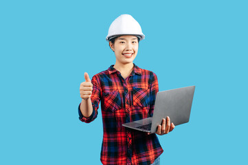 Young female engineer wearing helmet and use laptop computer