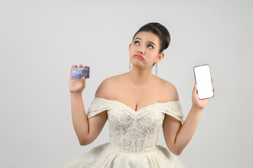 Young asian beautiful bride posting with credit card and smartphone in hand