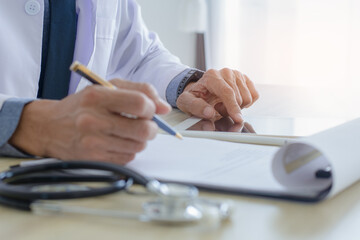 Doctor work on digital tablet computer and write prescription on clipboard.