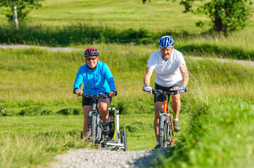 Raus ins Grüne mit dem Fahrrad - Eltern mit Nachwuchs im Buggy unterwegs mit dem Mountainbike