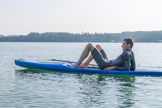 Stehpaddler beim entspannten Sonnenbad auf dem Board - die Seele baumeln lassen auf dem See