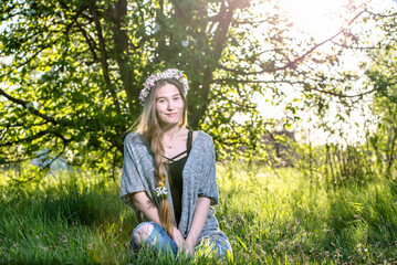 Smiling blonde girl posing with flower wreath on her long braided hair.