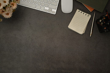 Simple workplace with keyboard, coffee cup, stationery and notebook on stone surface. Top view with copy space
