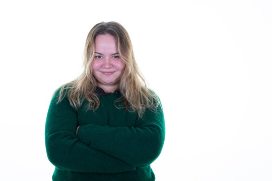 overweight woman in winter sweater green smiling and casually with arms crossed in white background