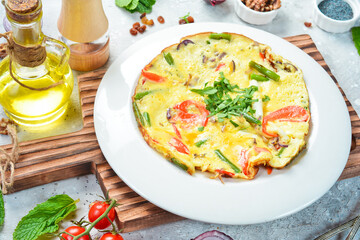 Breakfast. Omelette with cheese and vegetables. On a white plate. On a gray stone background. Restaurant menu.
