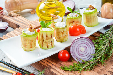 Zucchini rolls with feta cheese. On a white plate. On a gray stone background. Restaurant menu.