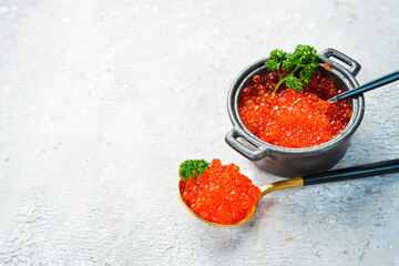 A spoon with red salmon caviar. Macro photo. Free space for text. On a concrete background.