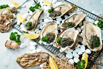 Fototapeta na wymiar Black caviar served with oysters and lemon, on ice. On a stone background. Top view. Rustic style.