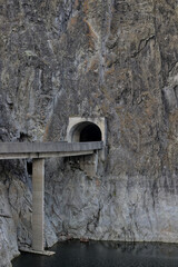 Entrance to a tunnel in a sheer cliff on the Transfagaras Highway in Romania. Dam and reservoir on Lake Vidraru. Construction of a hydroelectric power station, hydraulic structures.