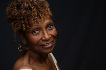 Closeup portrait of a beautiful retired elderly African American female  widow in her 70s with smiling expression and personality, one