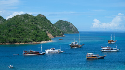 Landscape view of tropical islands with white sandy beaches and moored liveaboard tour boats in turquoise ocean in Labuan Bajo, Flores Island Indonesia