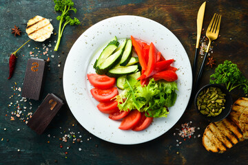 Assorted vegetables in a plate. Slicing fresh vegetables: cucumber, tomato, pepper. Restaurant menu. Top view.